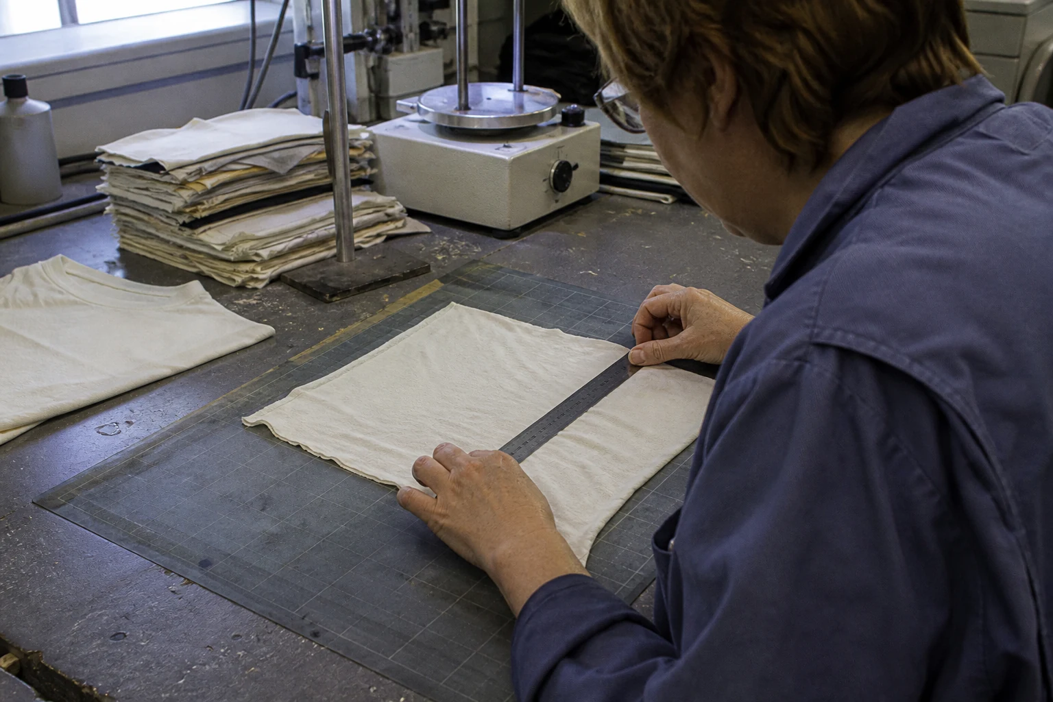 Technician measuring a cotton fabric swatch during a textile shrinkage test
